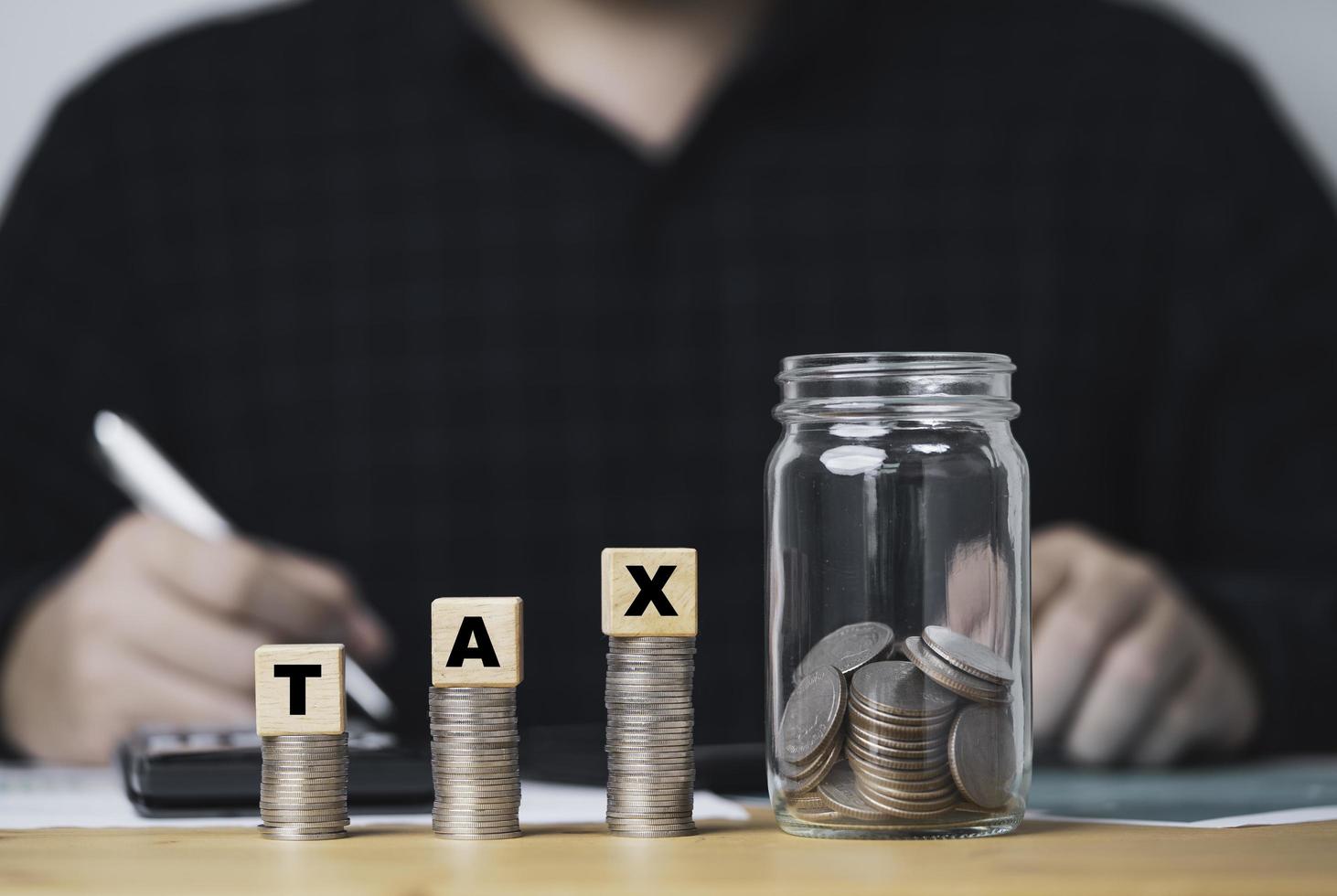 Accountants make accounts, income, expenses, annually to calculate taxation with coins stacking and saving jar for tax reduce and refund concept. photo