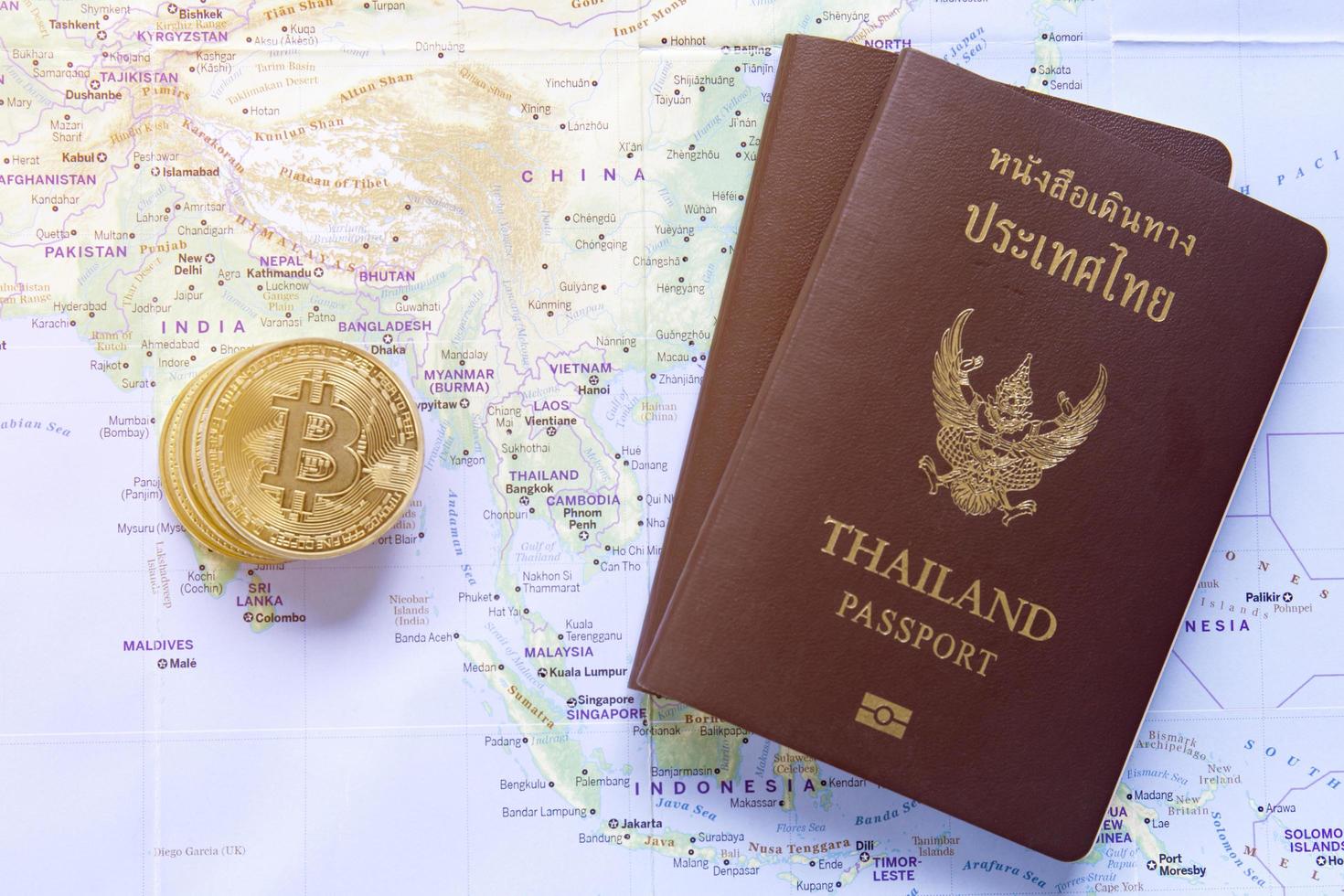 los bitcoins de oro y el pasaporte de tailandia se colocan en el mapa mundial. foto