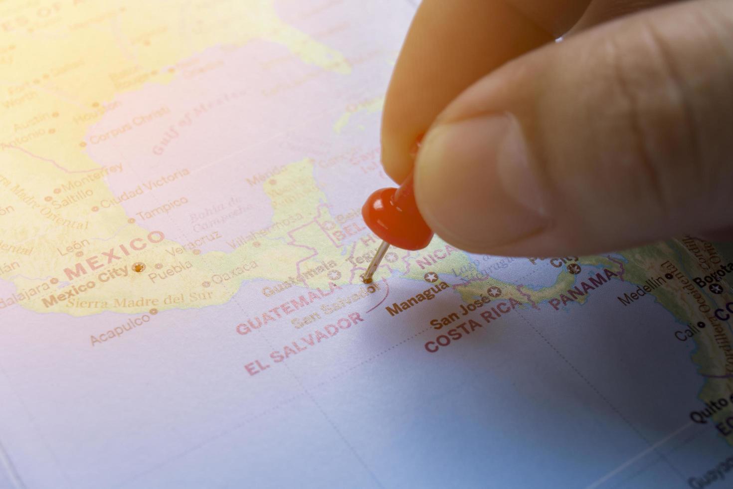 Hand pinned red on the world map of El Salvador. photo