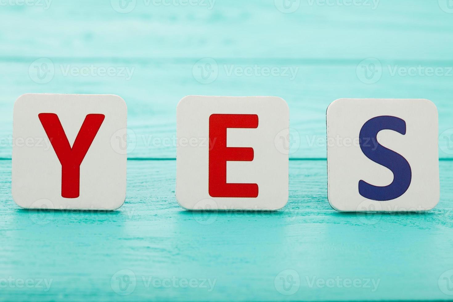 Word yes on blue wooden background. Selective focus. Copy space. photo