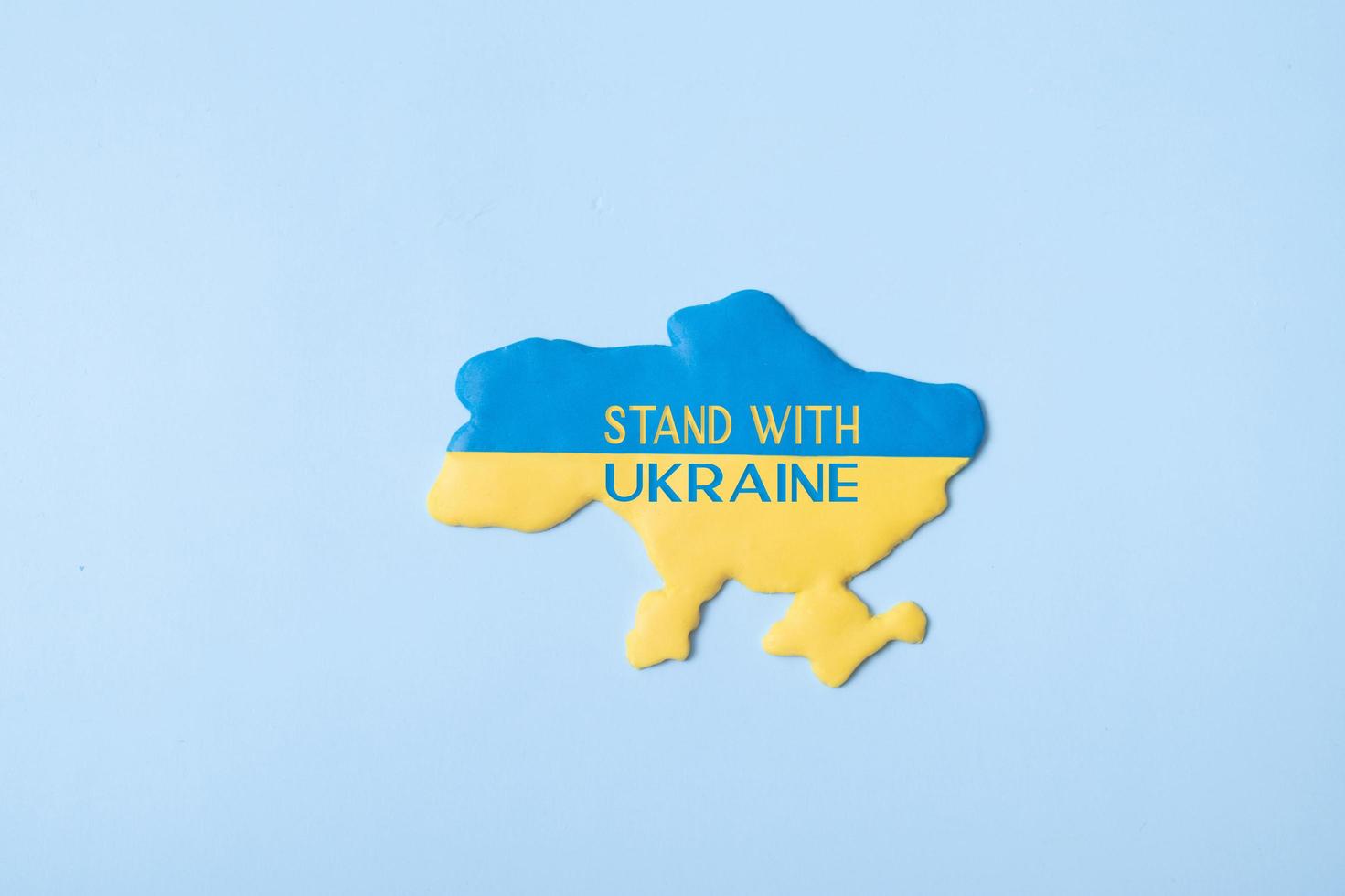 Stand with Ukraine text on tha map Ukraine in yellow-blue colors of the national flag on a blue background top view photo