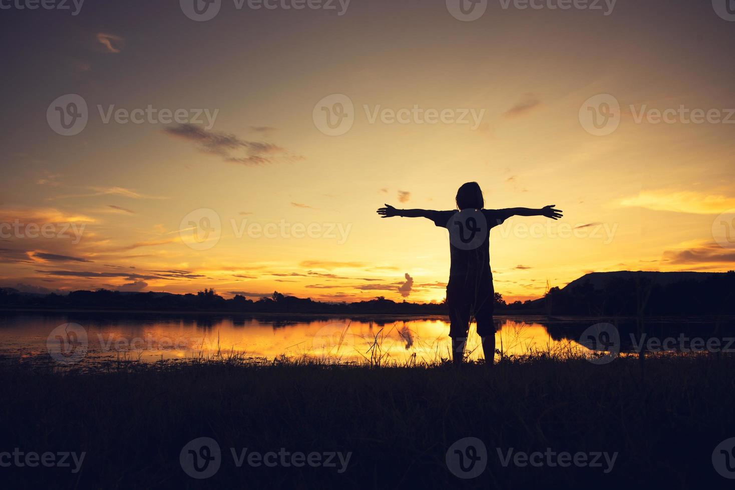 young woman standing and hand up on sunset photo