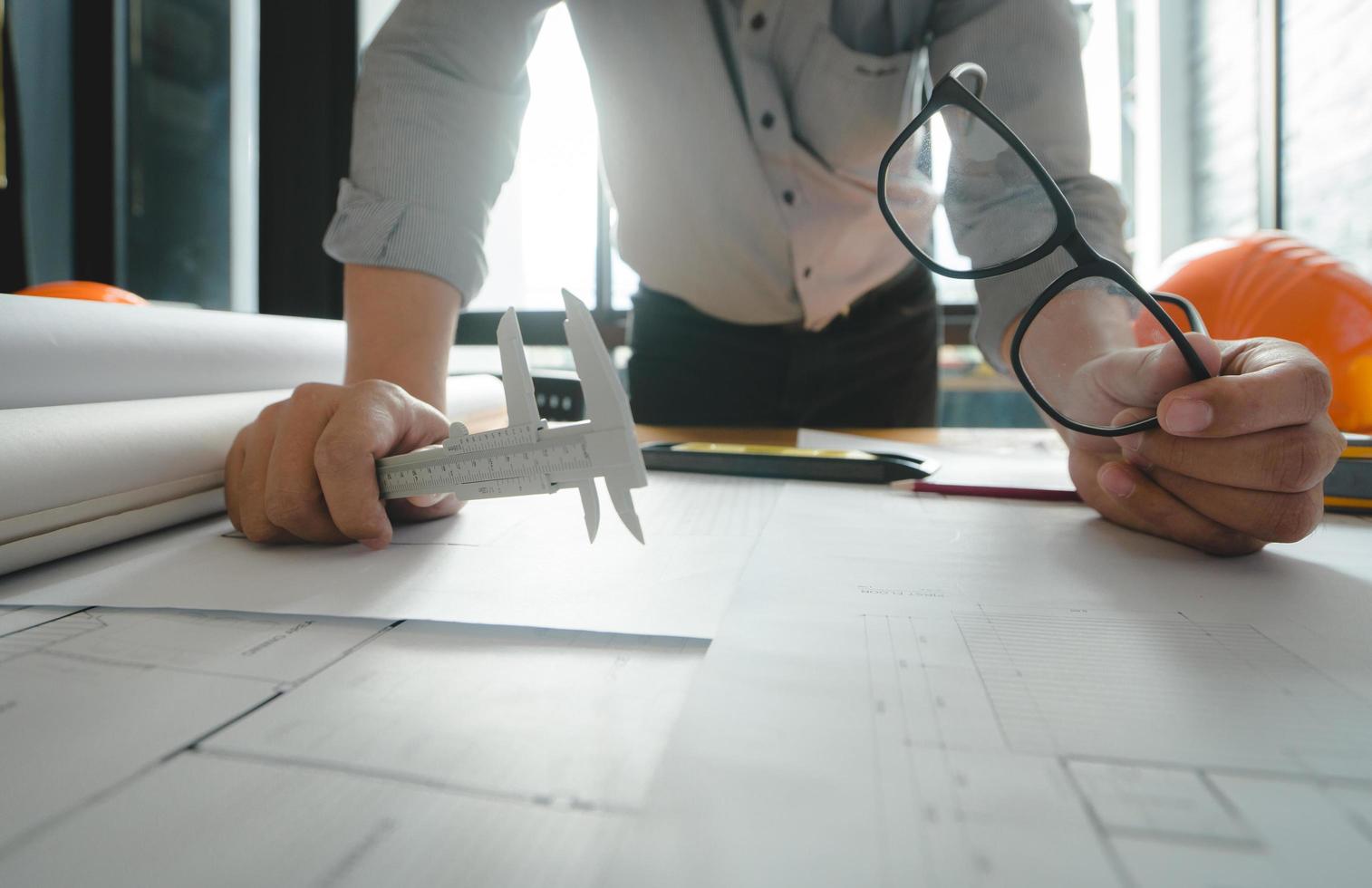 Hands of architect or engineer using drawing compass with blueprint on desk in office.Team of architects engineer discussing and check documents and business workflow.Construction concept. photo