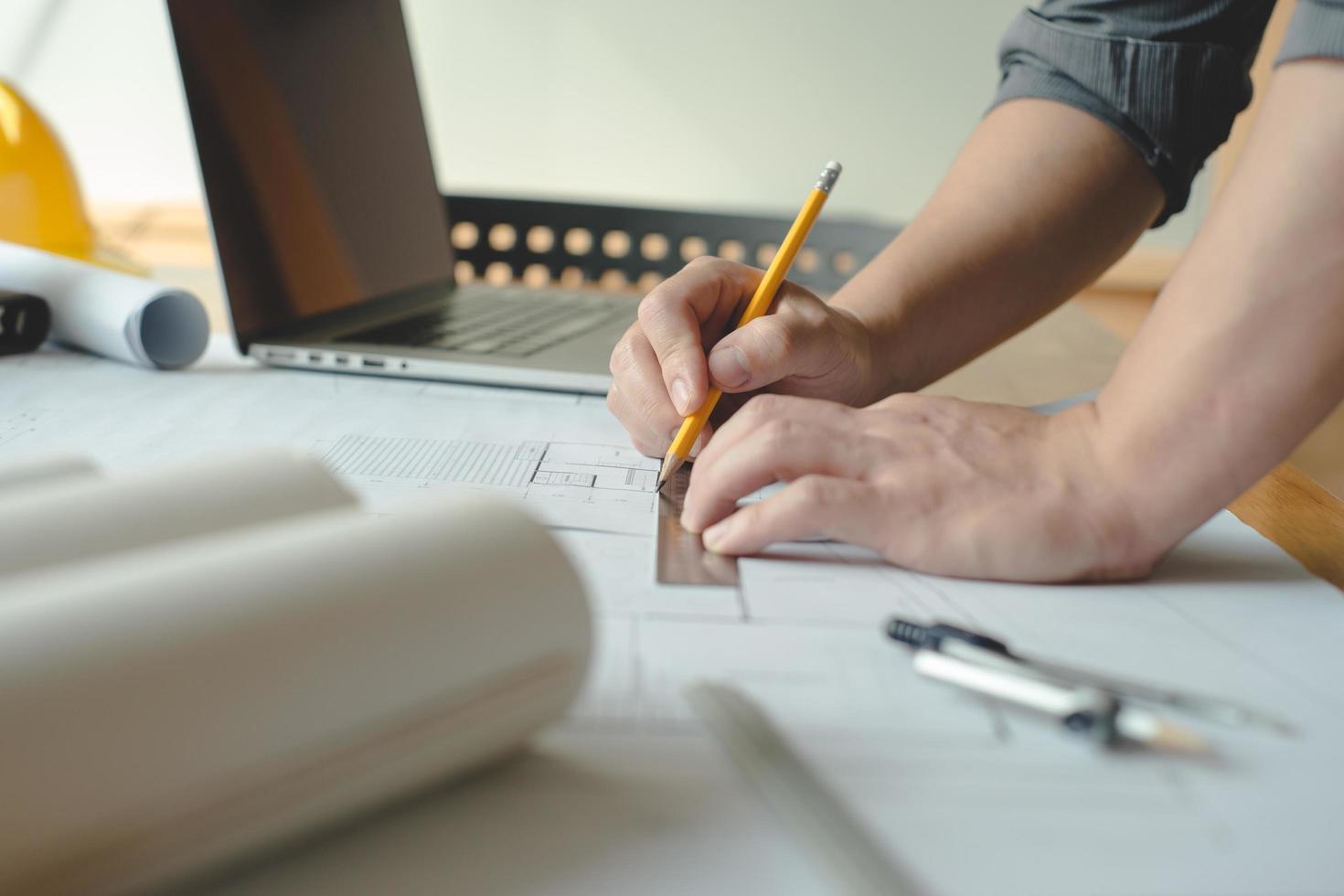 manos de arquitecto o ingeniero usando brújula de dibujo con plano en el escritorio en la oficina. equipo de arquitectos ingenieros discutiendo y verificando documentos y flujo de trabajo empresarial. concepto de construcción. foto