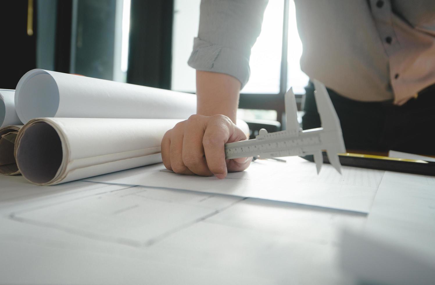 Hands of architect or engineer using drawing compass with blueprint on desk in office.Team of architects engineer discussing and check documents and business workflow.Construction concept. photo