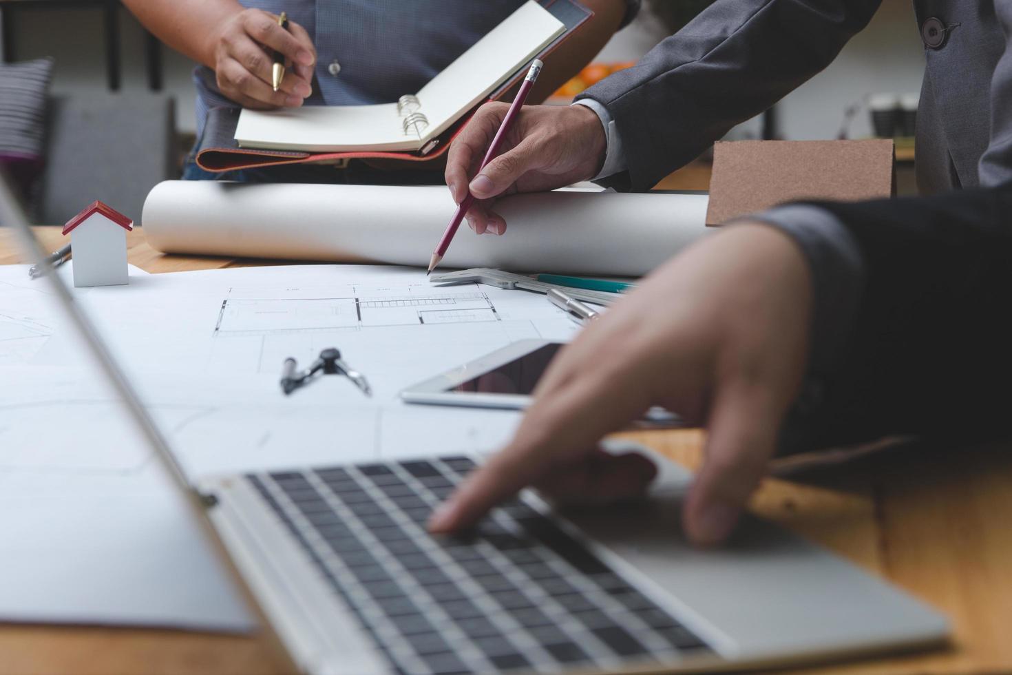 Hands of architect or engineer using drawing compass with blueprint on desk in office.Team of architects engineer discussing and check documents and business workflow.Construction concept. photo