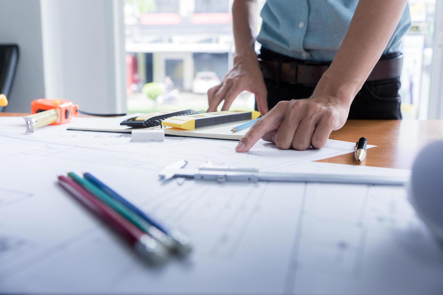 manos de arquitecto o ingeniero usando brújula de dibujo con plano en el escritorio en la oficina. equipo de arquitectos ingenieros discutiendo y verificando documentos y flujo de trabajo empresarial. concepto de construcción. foto