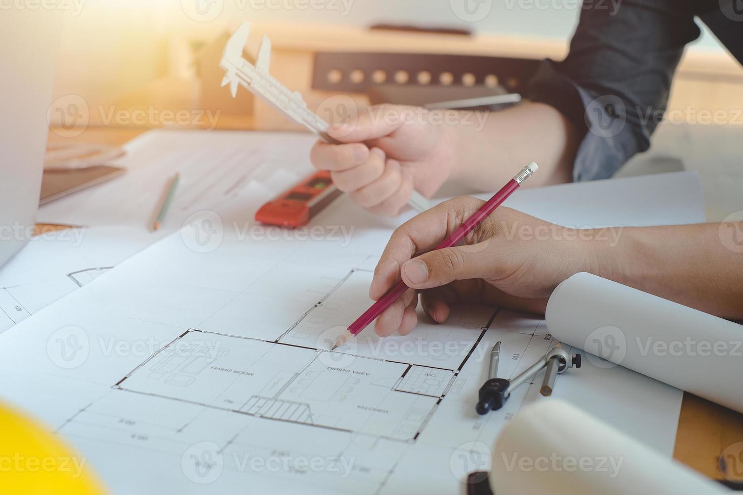 manos de arquitecto o ingeniero usando brújula de dibujo con plano en el escritorio en la oficina. equipo de arquitectos ingenieros discutiendo y verificando documentos y flujo de trabajo empresarial. concepto de construcción. foto