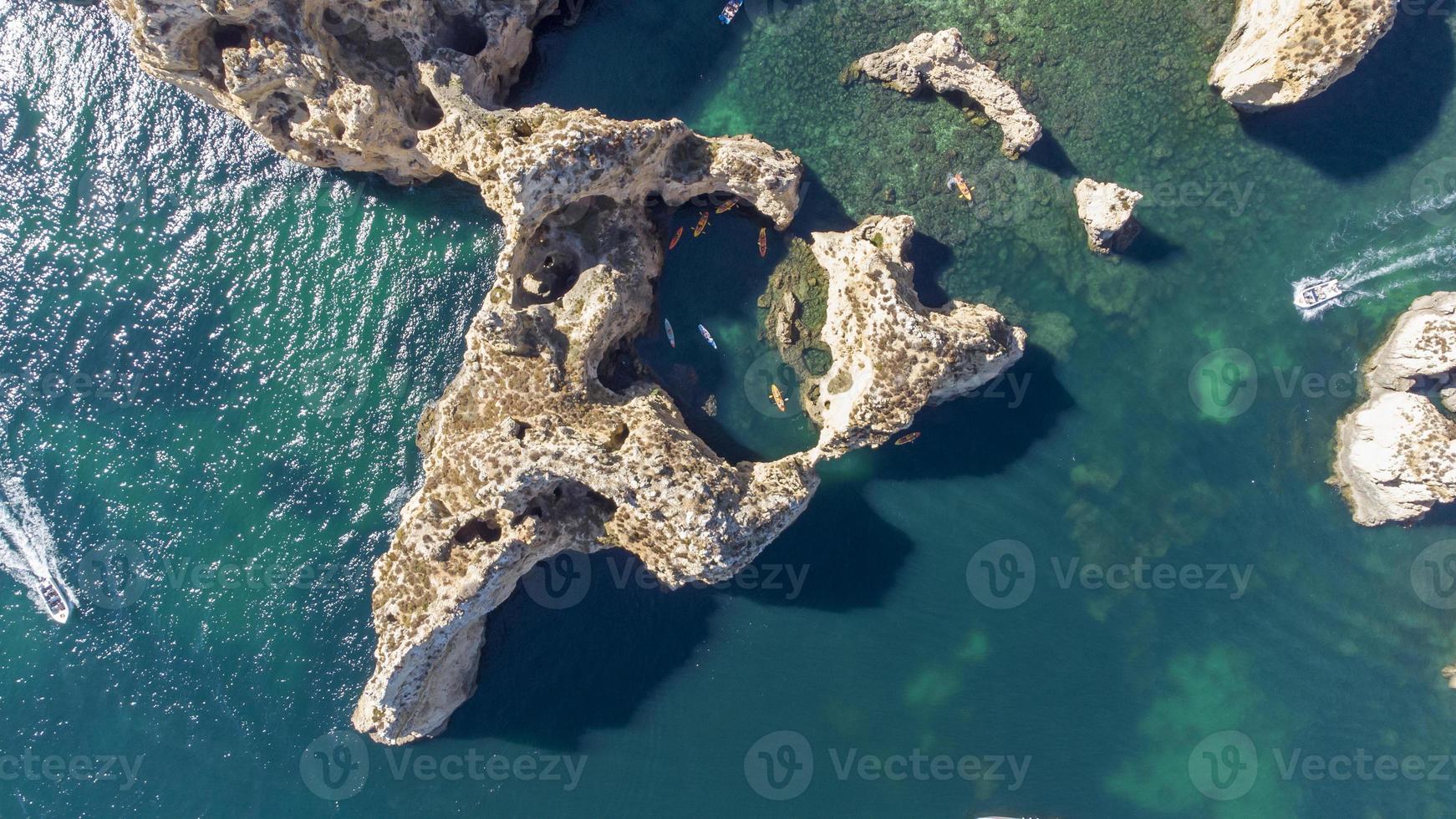 Aerial drone shot of kayaks and boats passing around magical Ponta da Piedade limestone cliffs. Exploring caves and tunnels of Lagos, Algarve, South of Portugal. Travel and adventure. Nomad life. photo