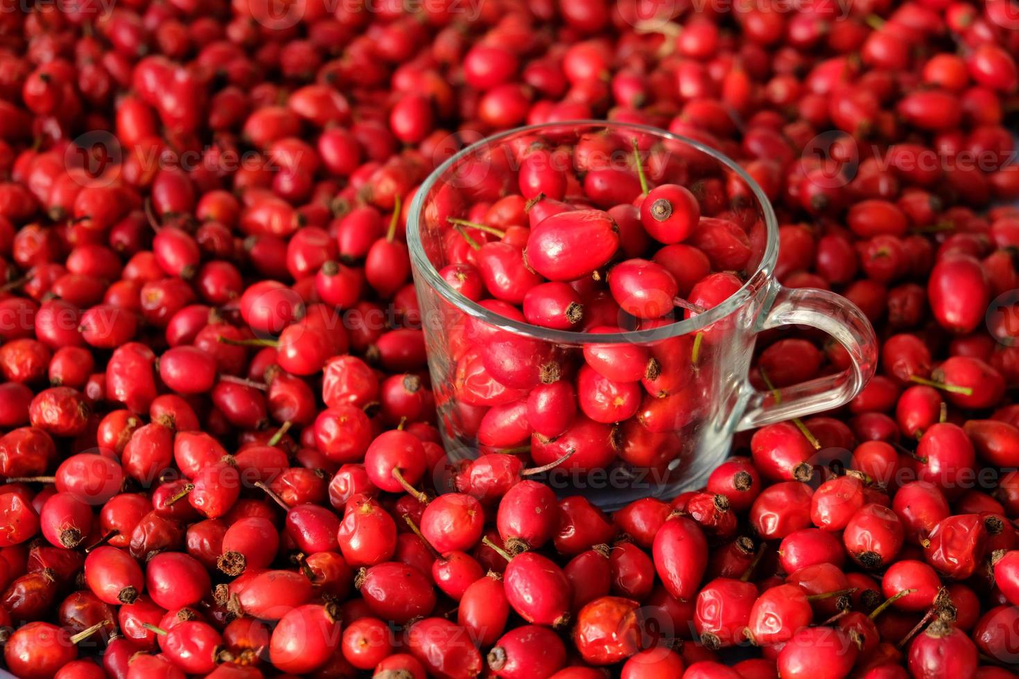 Rose hip or rosehip inside of the glass and over the table. Empty space for copy paste. Backgrounds and textures. Red vibrant colors. Cinematic. Wild fruits and healthy food. photo