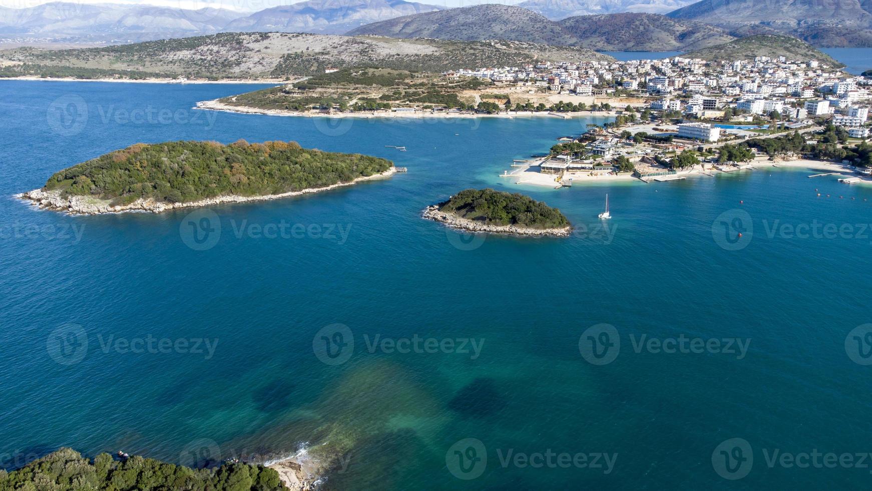 Aerial drone view of the beautiful seaside coast on a sunny day. Marvelous blue colors. Holidays and relaxing mood. Islands and boats. Amazing beaches to mediate and cure the soul. Vibrant colors. photo