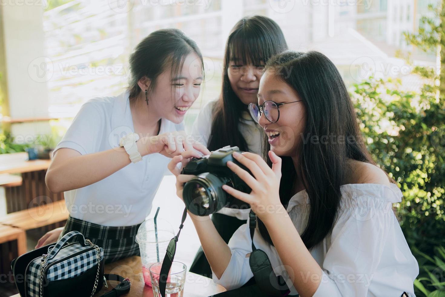 grupo de adolescentes asiáticos mirando la imagen en la pantalla de la cámara dslr con cara de felicidad foto