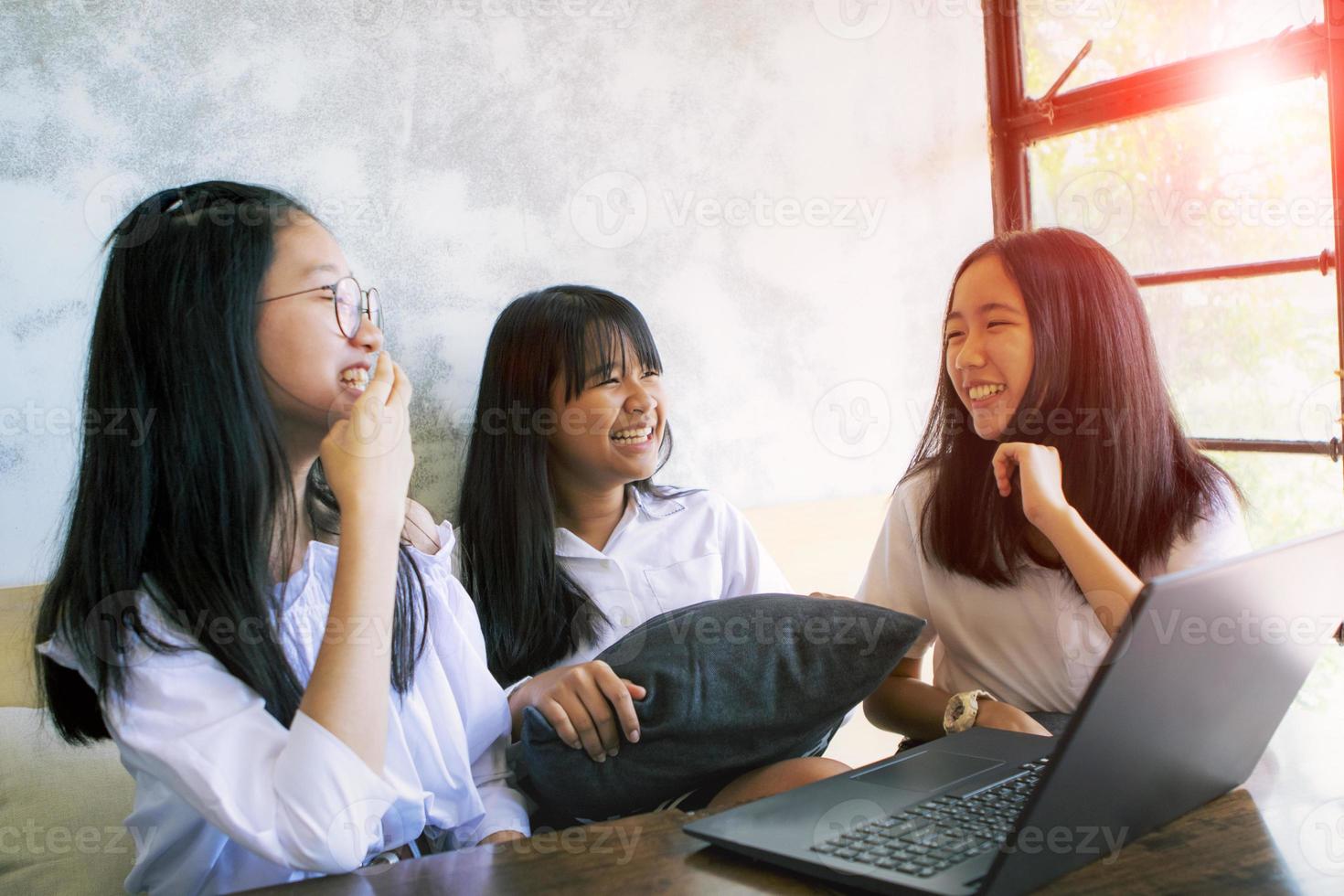 three asian teenager laughing with happiness face while working on aptop in living room photo