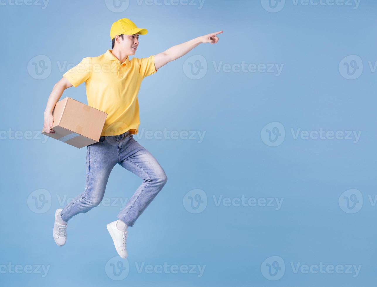 Full length image of Asian delivery man on blue background photo