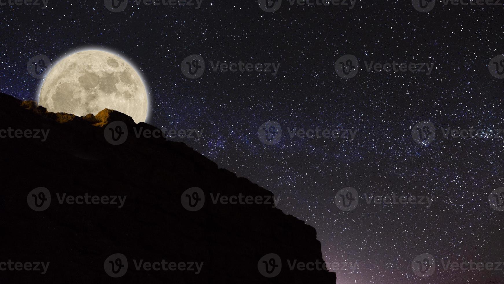 Fotografía con poca luz y larga exposición del cielo nocturno con una montaña a la derecha. textura granulada y fondo de enfoque suave. cielo nocturno vía láctea con luna llena y constelación del universo en la ba foto