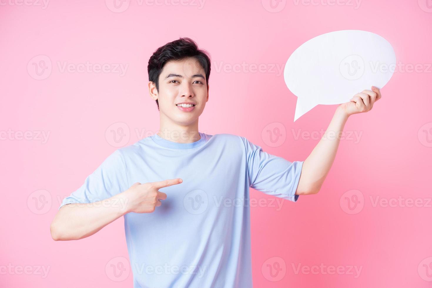 Image of young Asian man holding message bubble on pink background photo