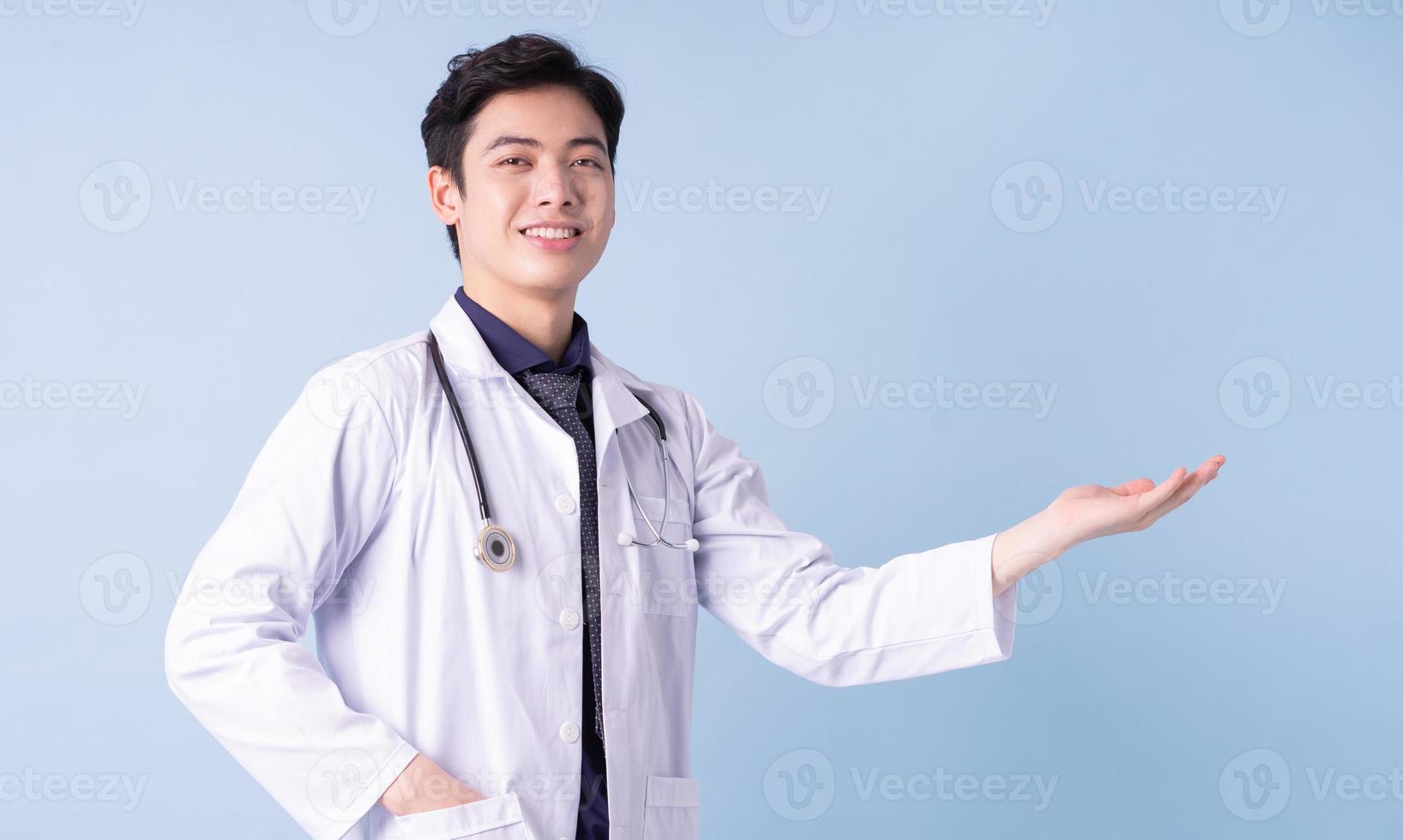 Portrait of young Asian male doctor on blue background photo