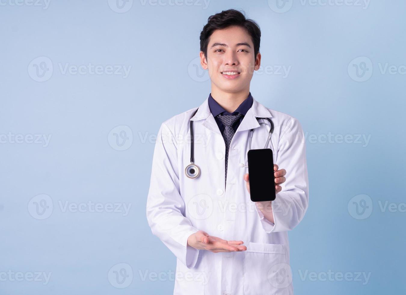 Portrait of young Asian male doctor on blue background photo