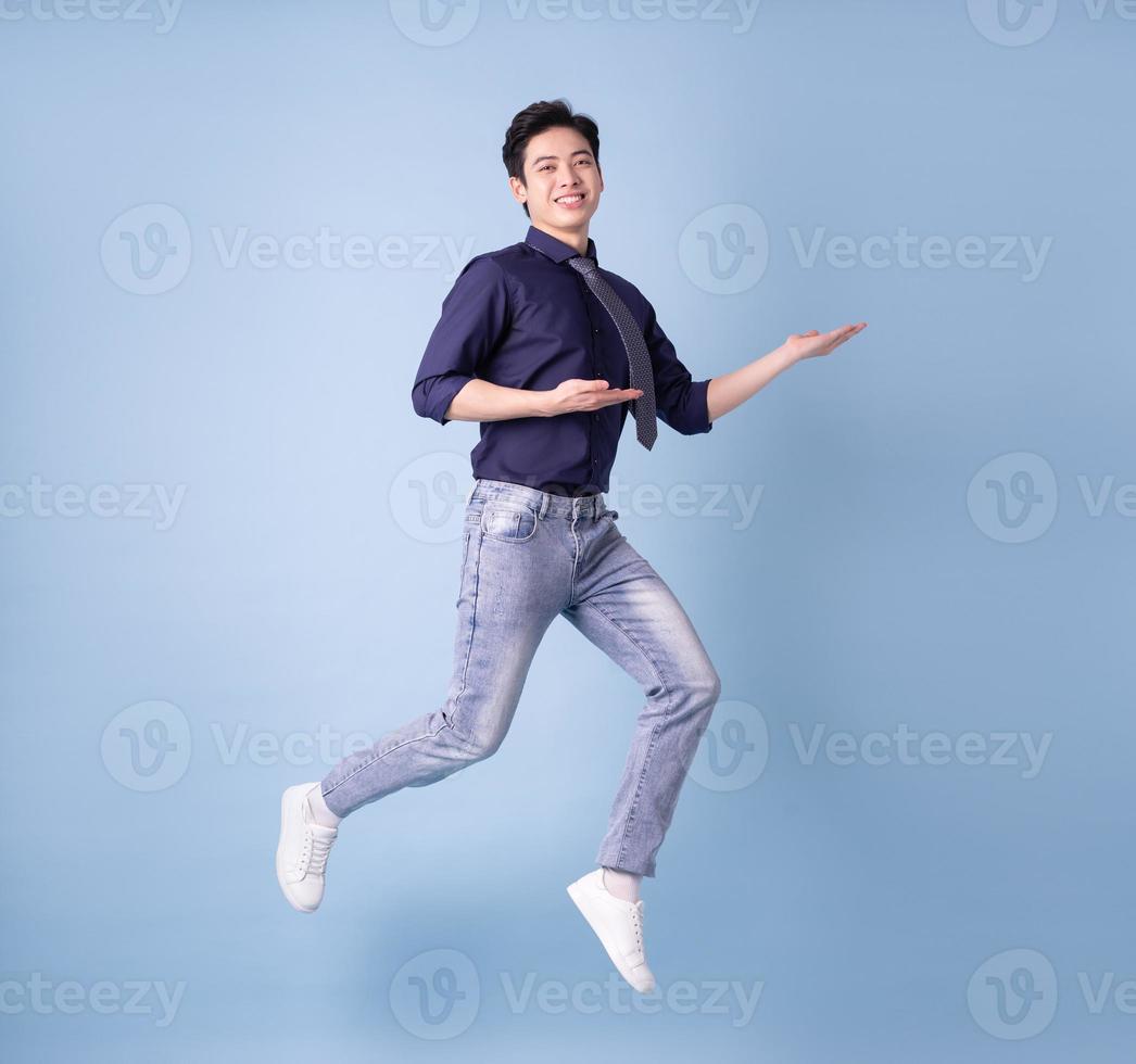 Full length image of young Asian businessman on blue background photo