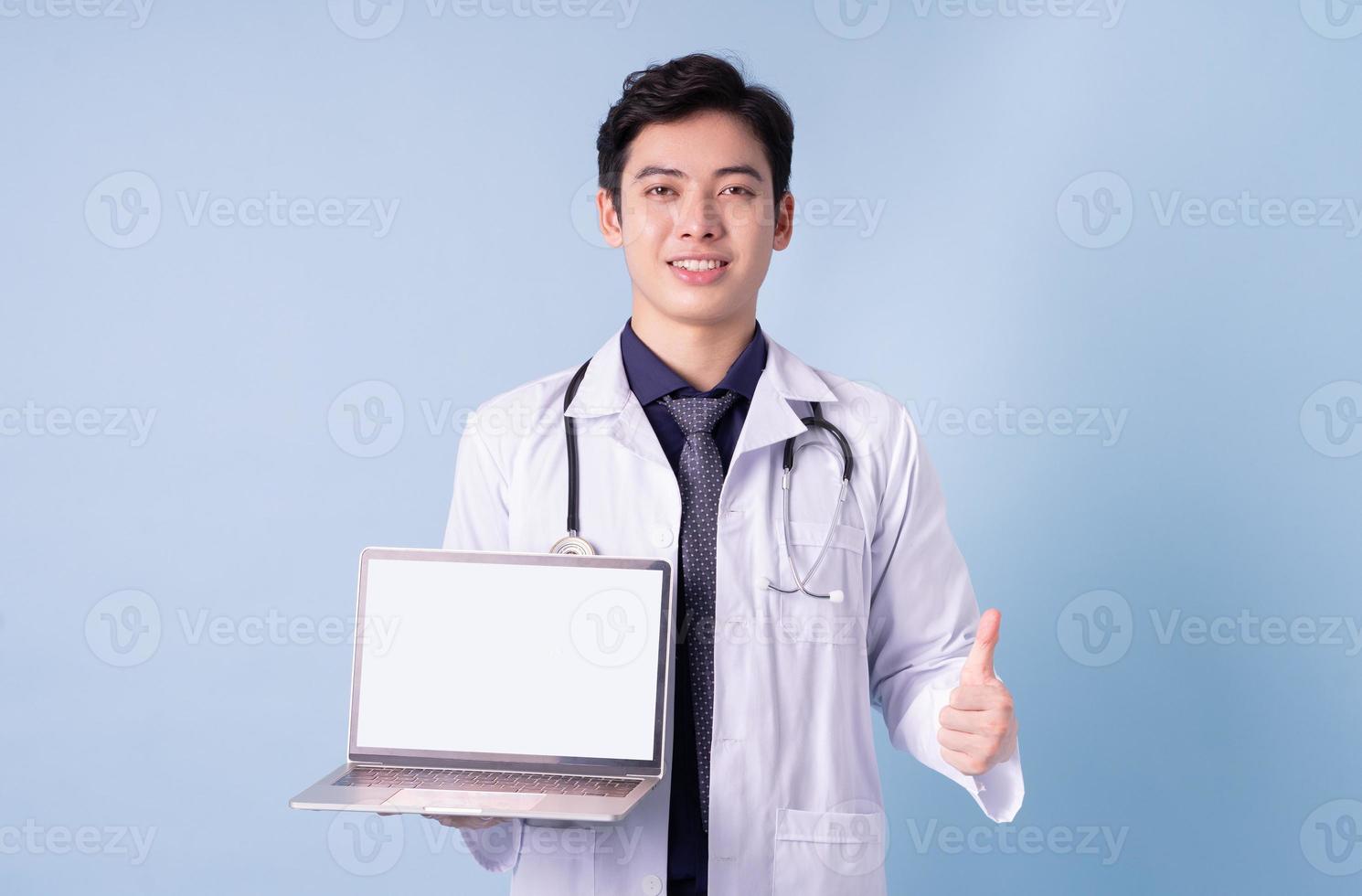 Portrait of young Asian male doctor on blue background photo