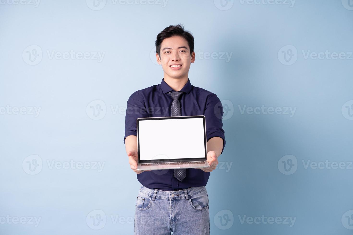 Portrait of young Asian businessman using laptop on blue background photo