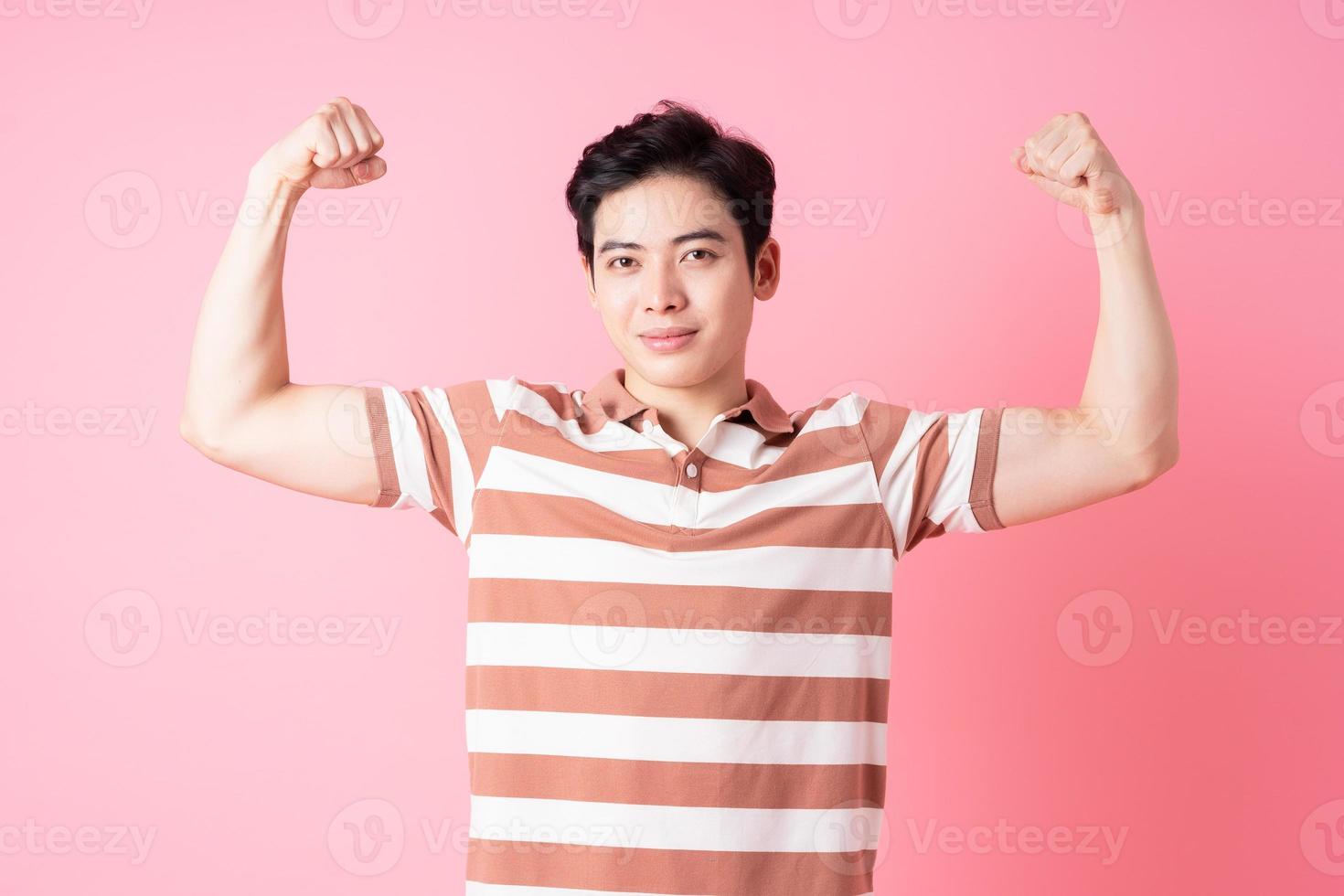 Young Asian man posing on pink background photo