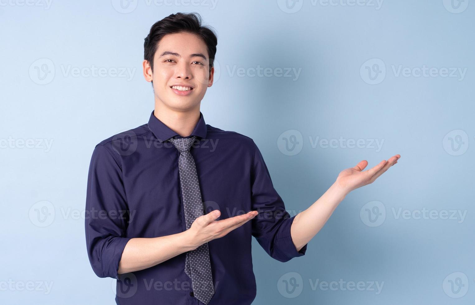 Portrait of young Asian businessman posing on blue background photo