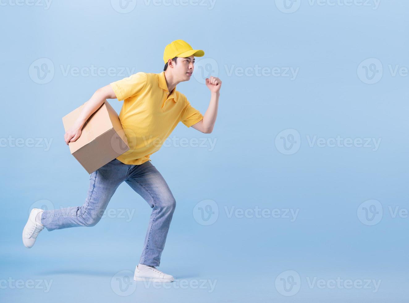 Full length image of Asian delivery man on blue background photo