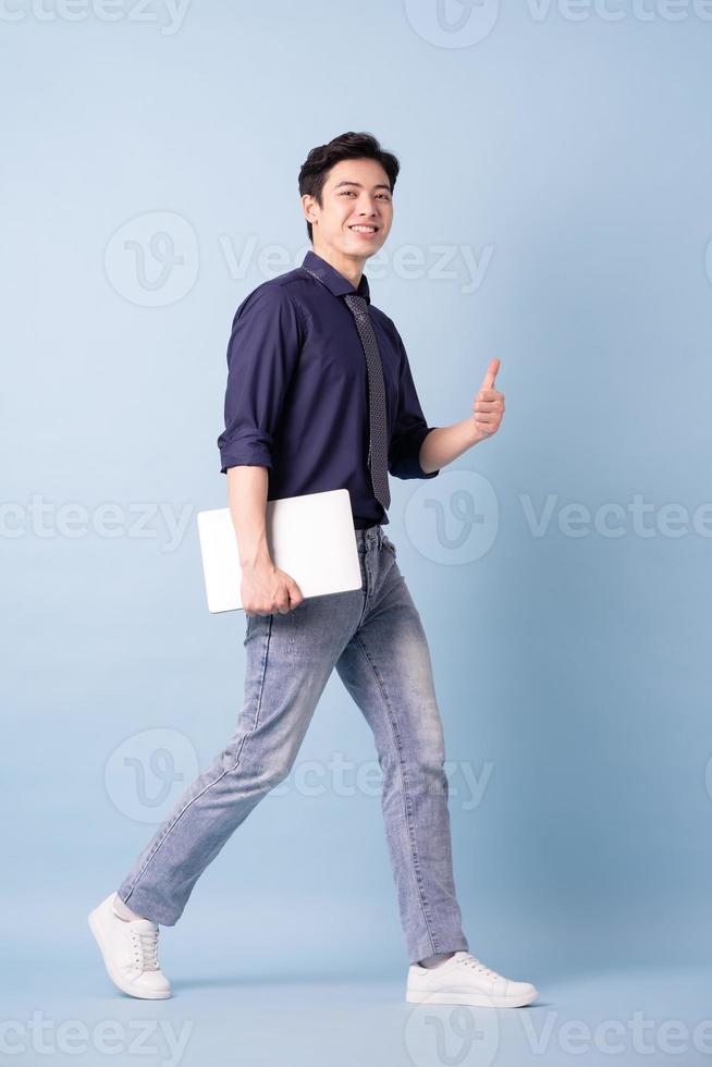 Full length image of young Asian businessman on blue background photo