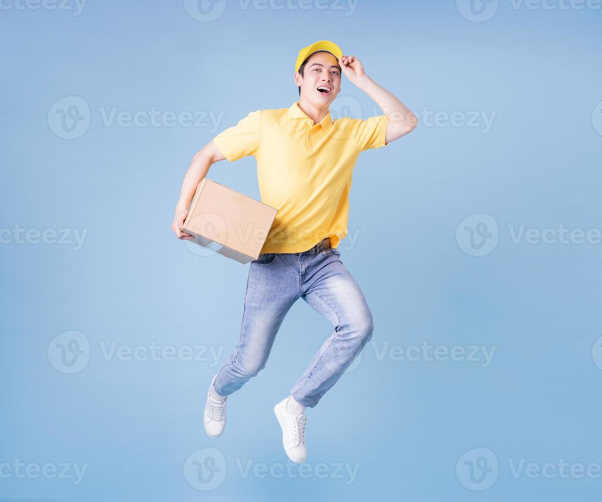 Full length image of Asian delivery man on blue background photo