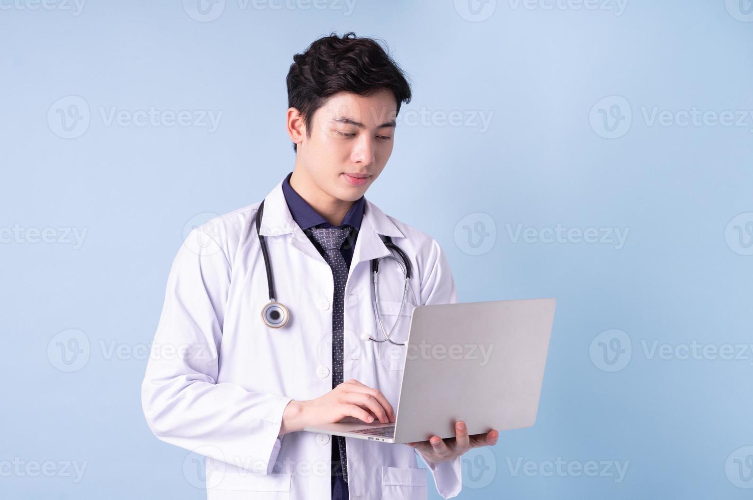 Portrait of young Asian male doctor on blue background photo