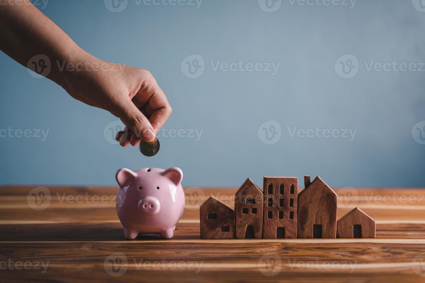Money Savings for Future Property House Concept, Hand is Putting Coin Into Piggy Bank for Saving Future Housing Real Estate Ownership. Banking Fund for Investing House Asset and Real Estate photo