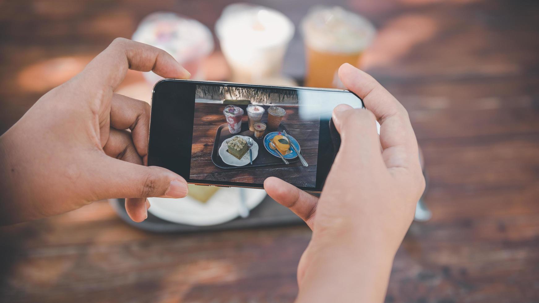 Woman Hands Taking Photographs Foods on Her Mobile Phone, Customer Woman Using Smartphone Take a Picture Food for Sharing Her Friends in Cafe and Restaurant Shop. Technology Digital Smart Phone photo