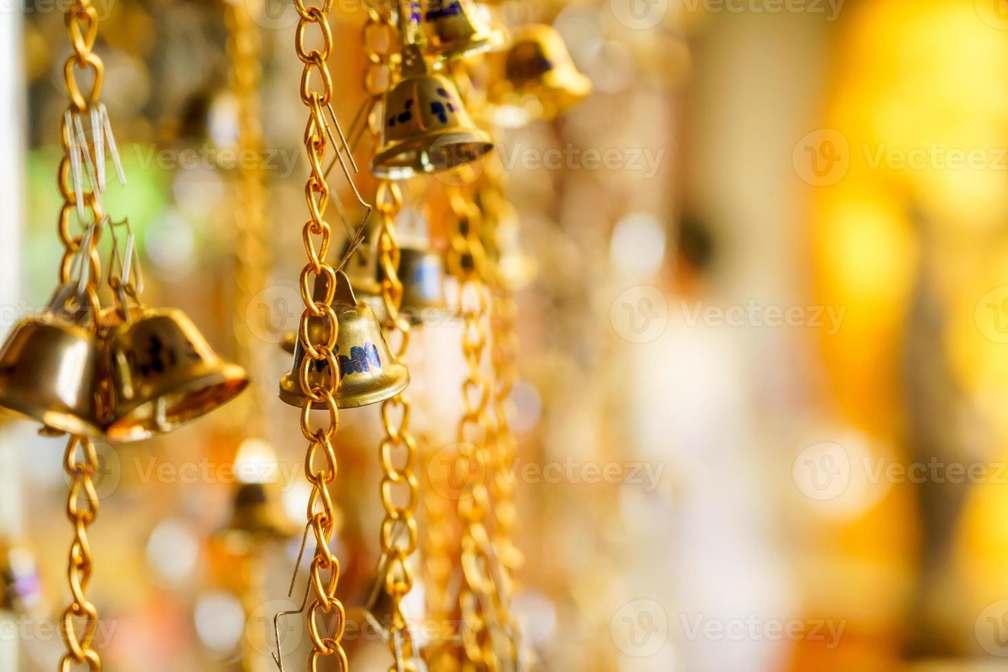 The golden bell hanging on a chain has a blurred background. photo