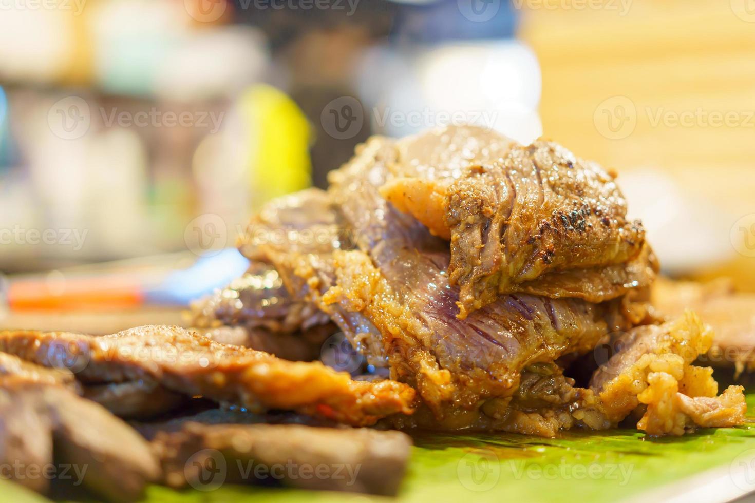 carne asada descansando sobre hojas de plátano y fondo borroso. foto