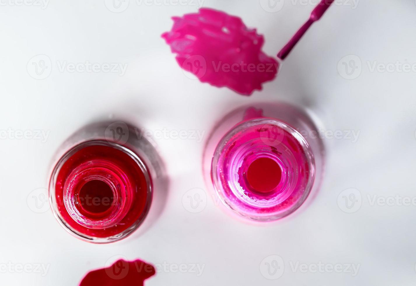 Opened bottles of nail polish on white background photo
