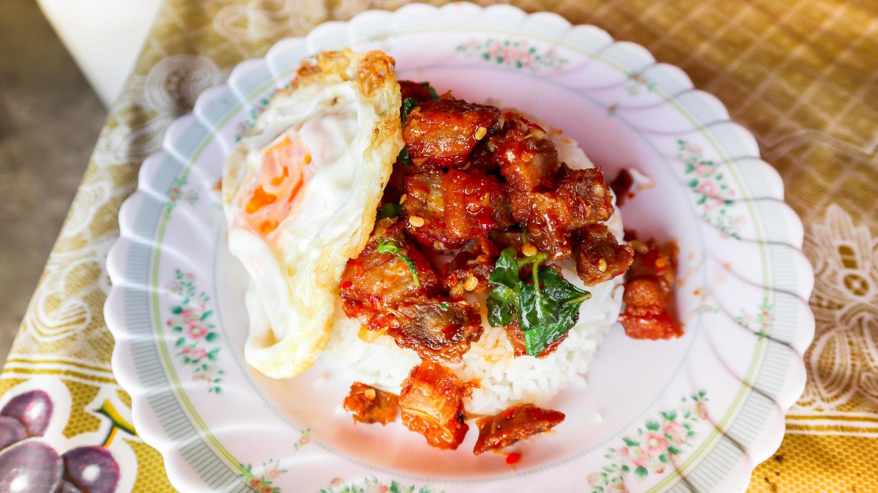 Stir fried crispy pork with chilli and basil, Thai spicy food eat with sunny side up fried egg. photo