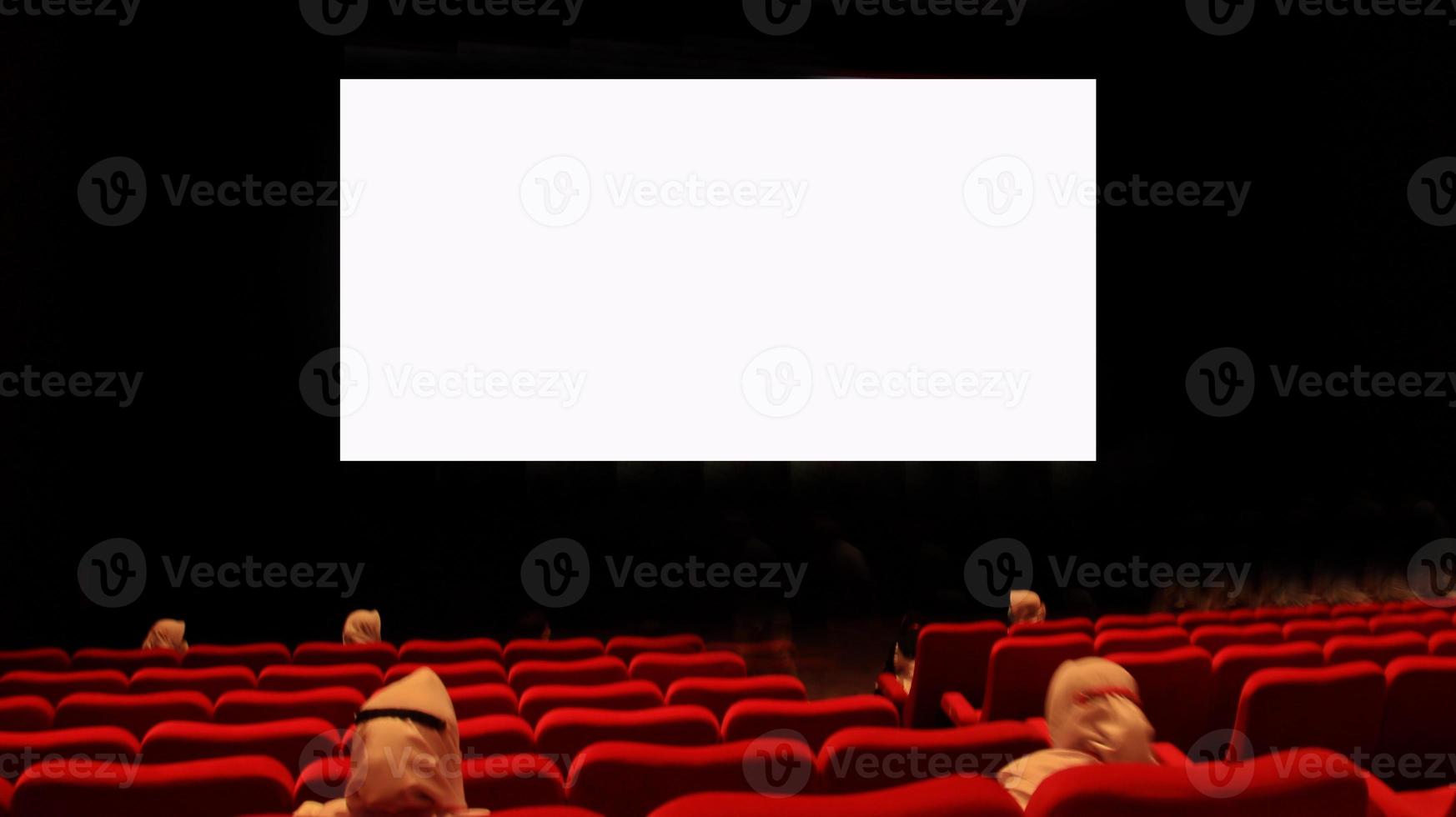 People in the cinema auditorium with empty white screen. photo