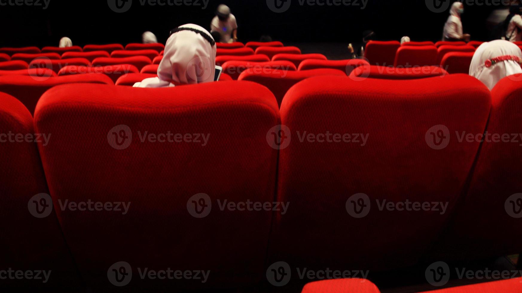 People in the cinema auditorium with empty white screen. photo