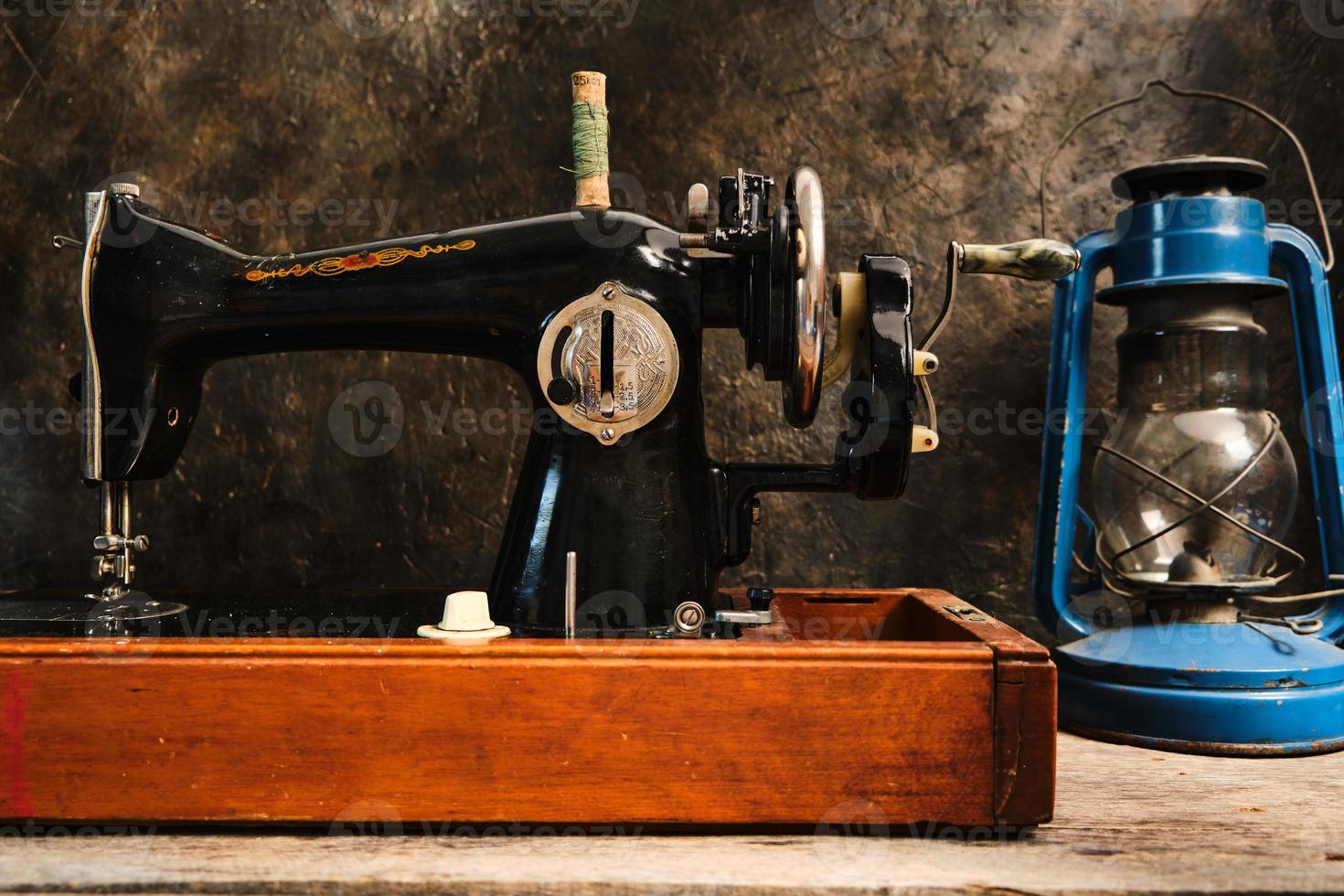 máquina de coser antigua, retro, vintage y una lámpara de queroseno sobre un fondo oscuro de una pared abstracta. foto
