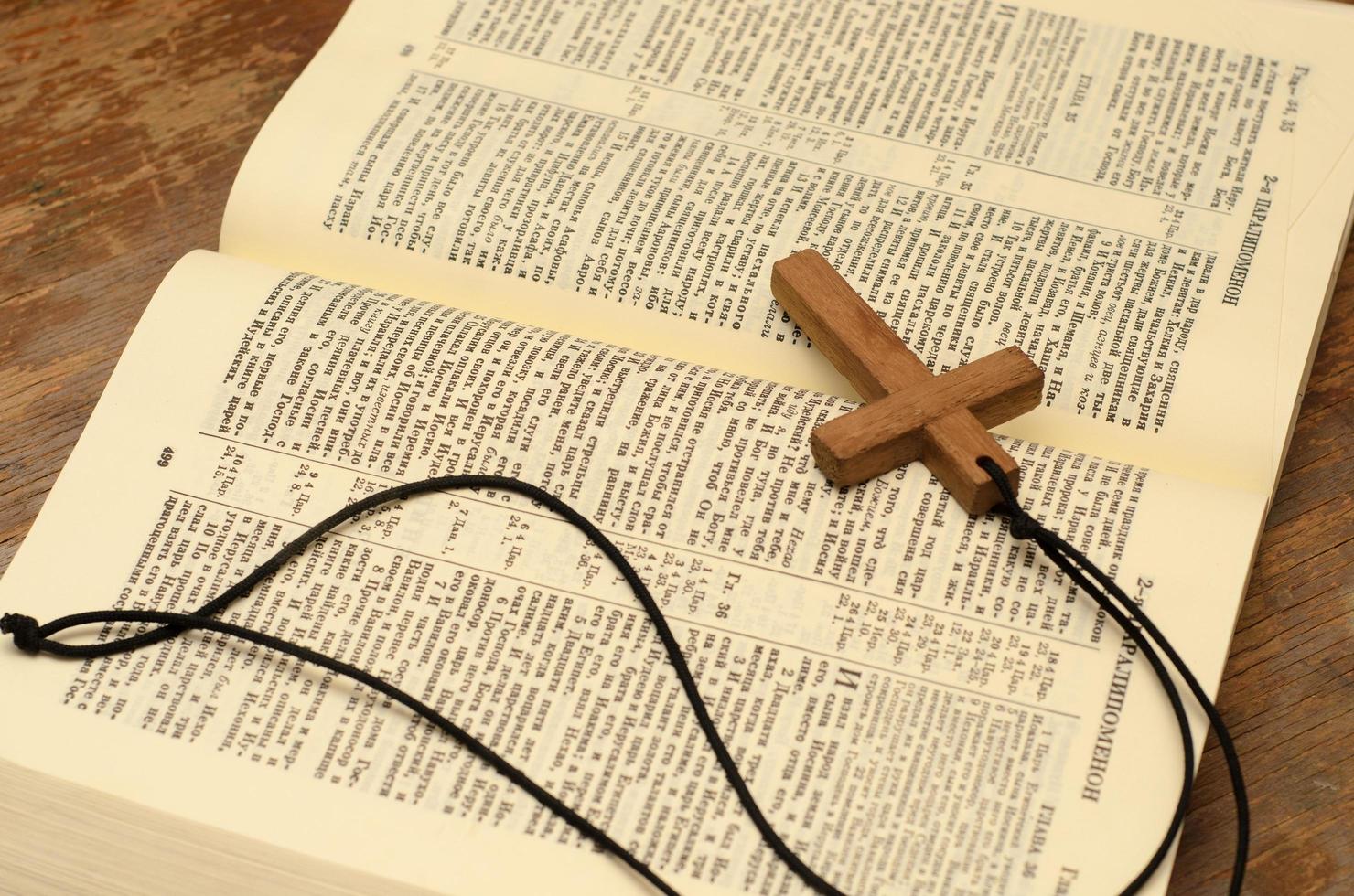 cruz cristiana de madera con cuerda en la santa biblia abierta. foto