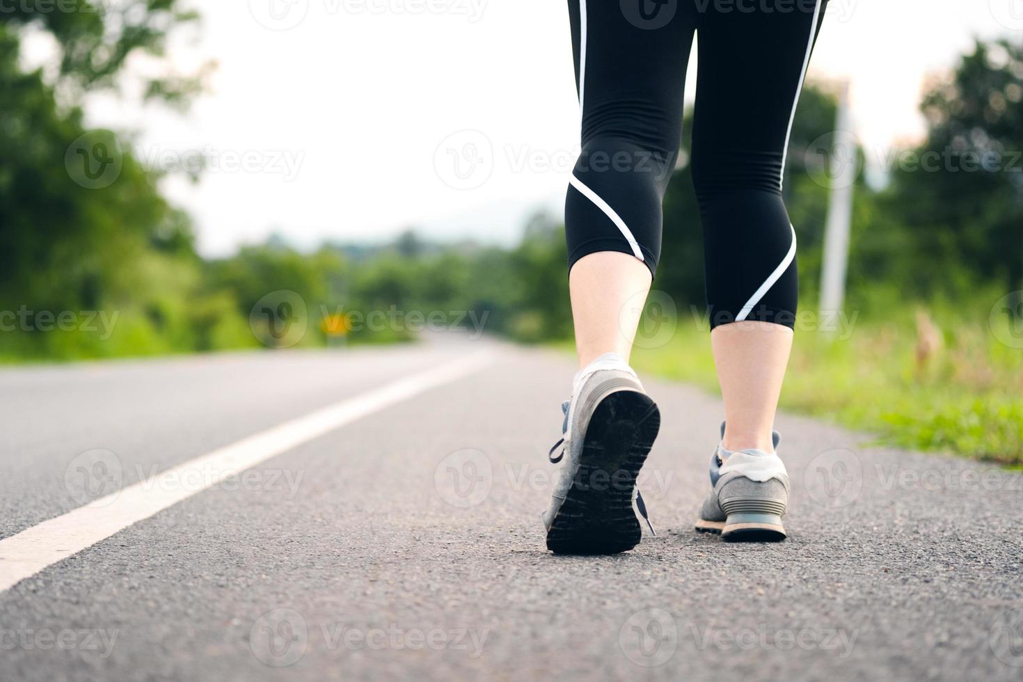 las mujeres jóvenes se paran para prepararse para caminar o trotar en un camino rural. vista posterior de las piernas femeninas. concepto de cuidado de la salud con ejercicio. foto