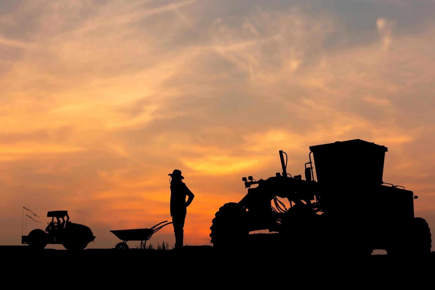 Silhouette of worker and grader at construction site, Road construction worker and compactors with blurred compactors sunset background photo