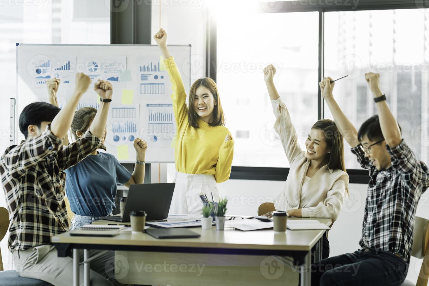 Happy successful asian business team giving a high fives gesture as they laugh and cheer their success. photo