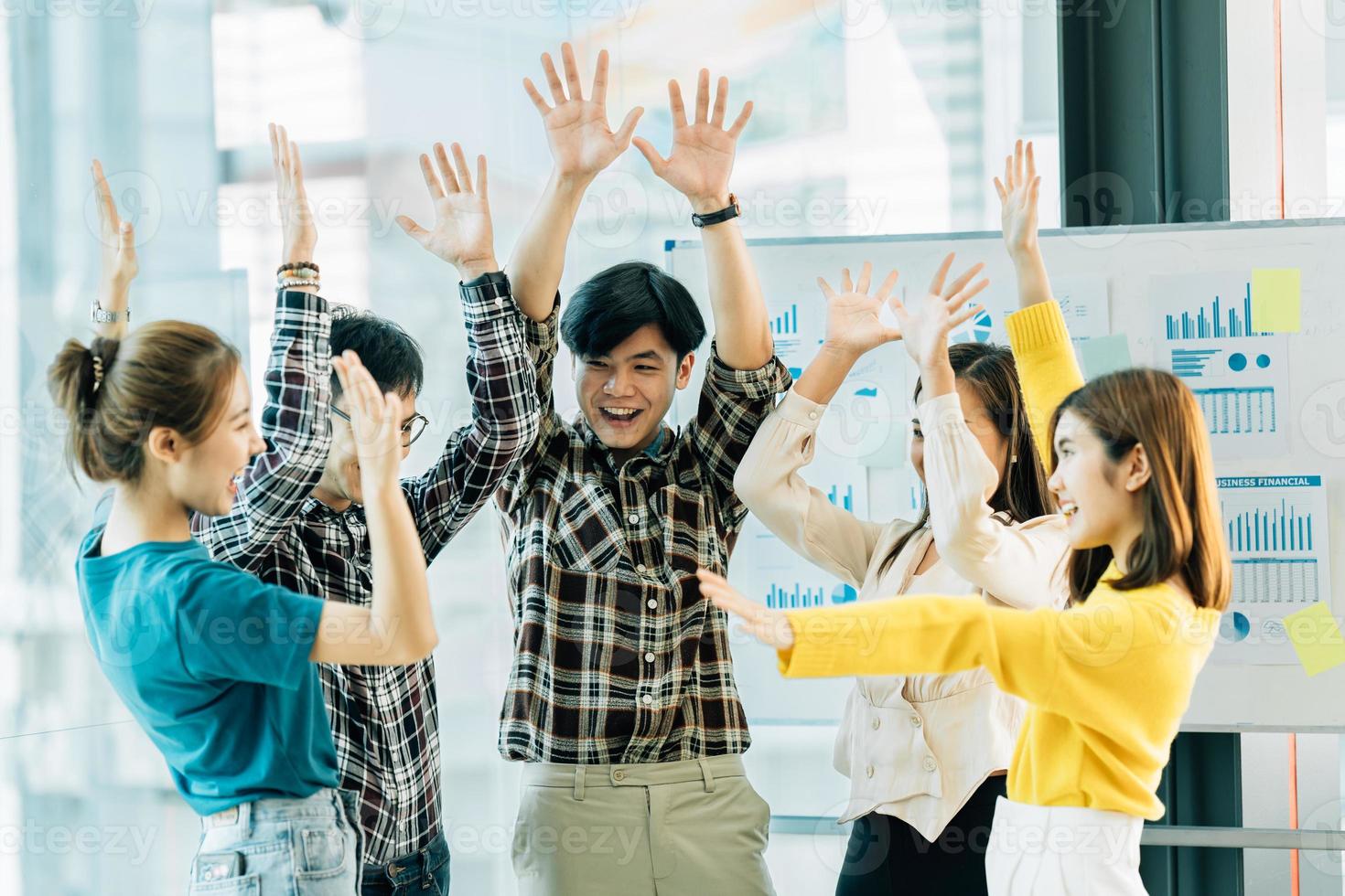 Happy successful asian business team giving a high fives gesture as they laugh and cheer their success. photo