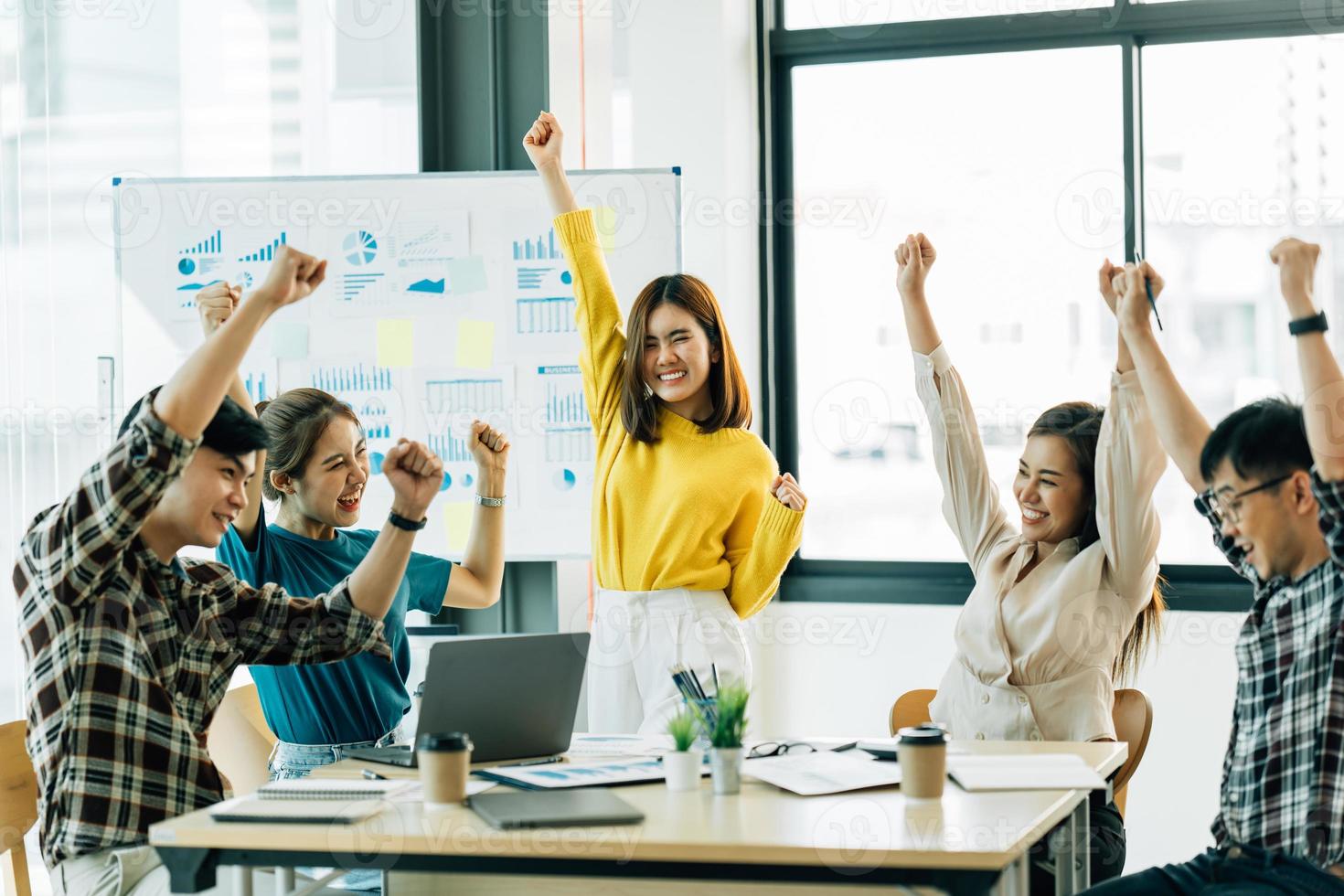 feliz y exitoso equipo de negocios asiático dando un gesto de chocar los cinco mientras se ríen y animan su éxito. foto