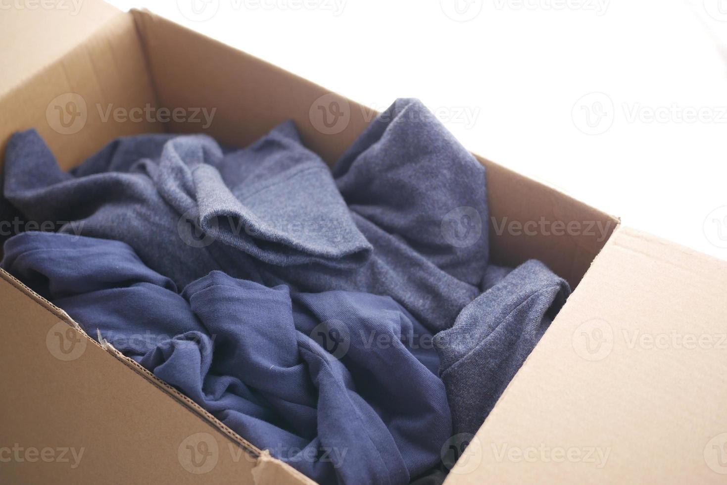 Donation box with donation clothes on a wooden table . photo