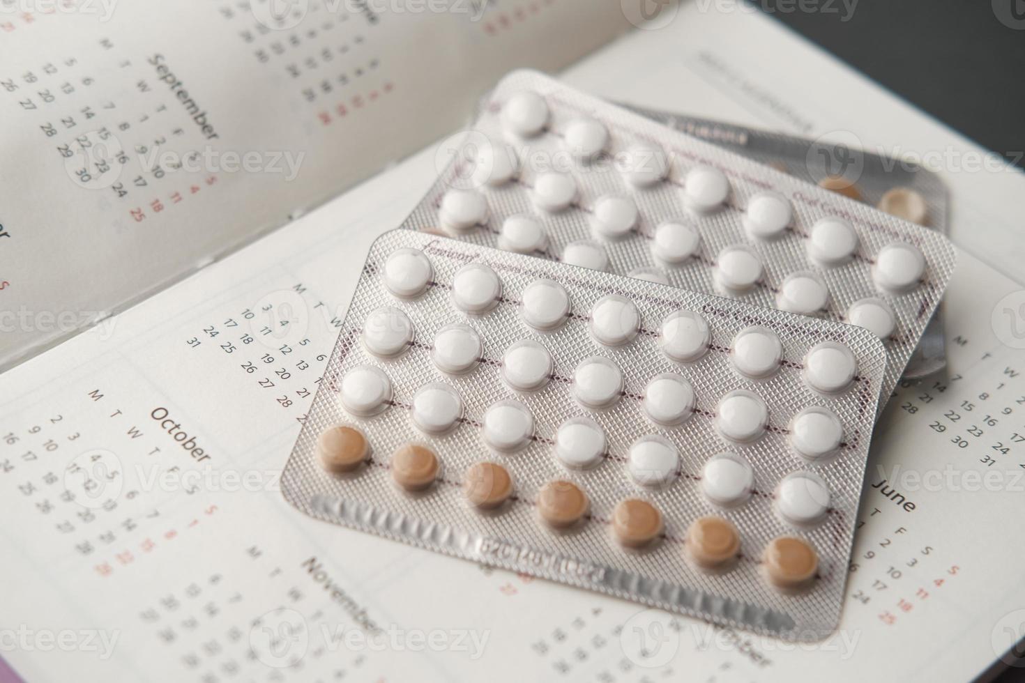 Píldoras anticonceptivas, calendario y bloc de notas en la mesa foto