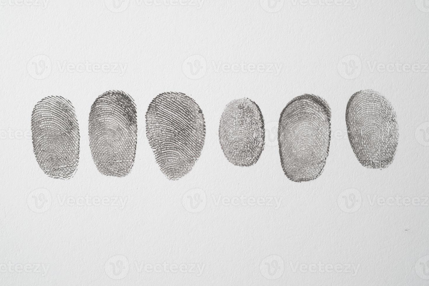 different black fingerprints on a paper close up , photo