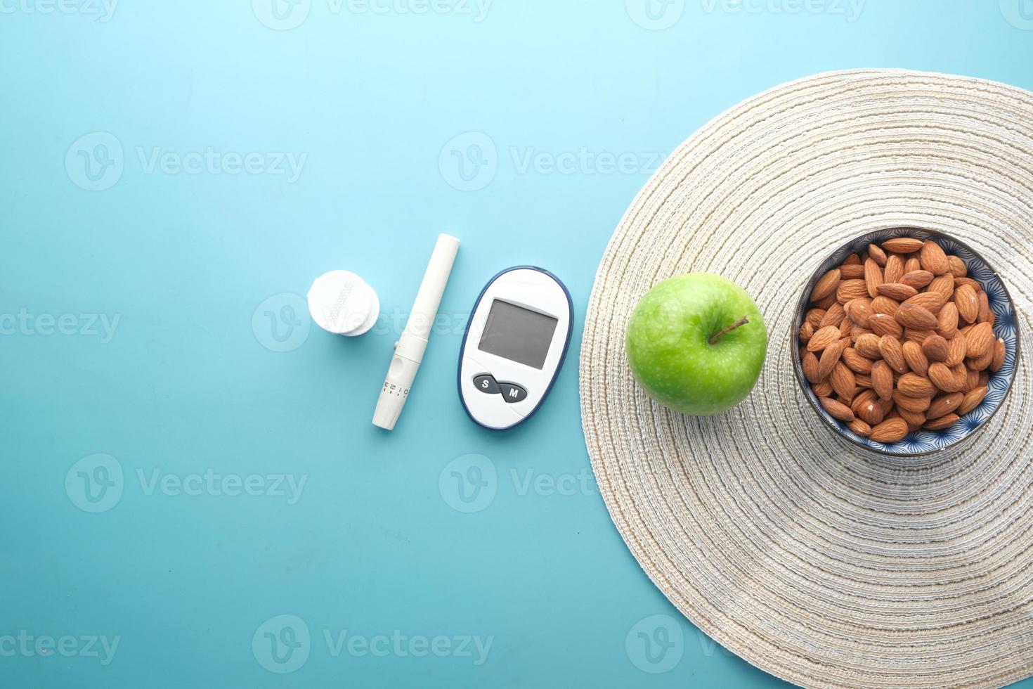 diabetic measurement tools, almond nut and apple on table photo